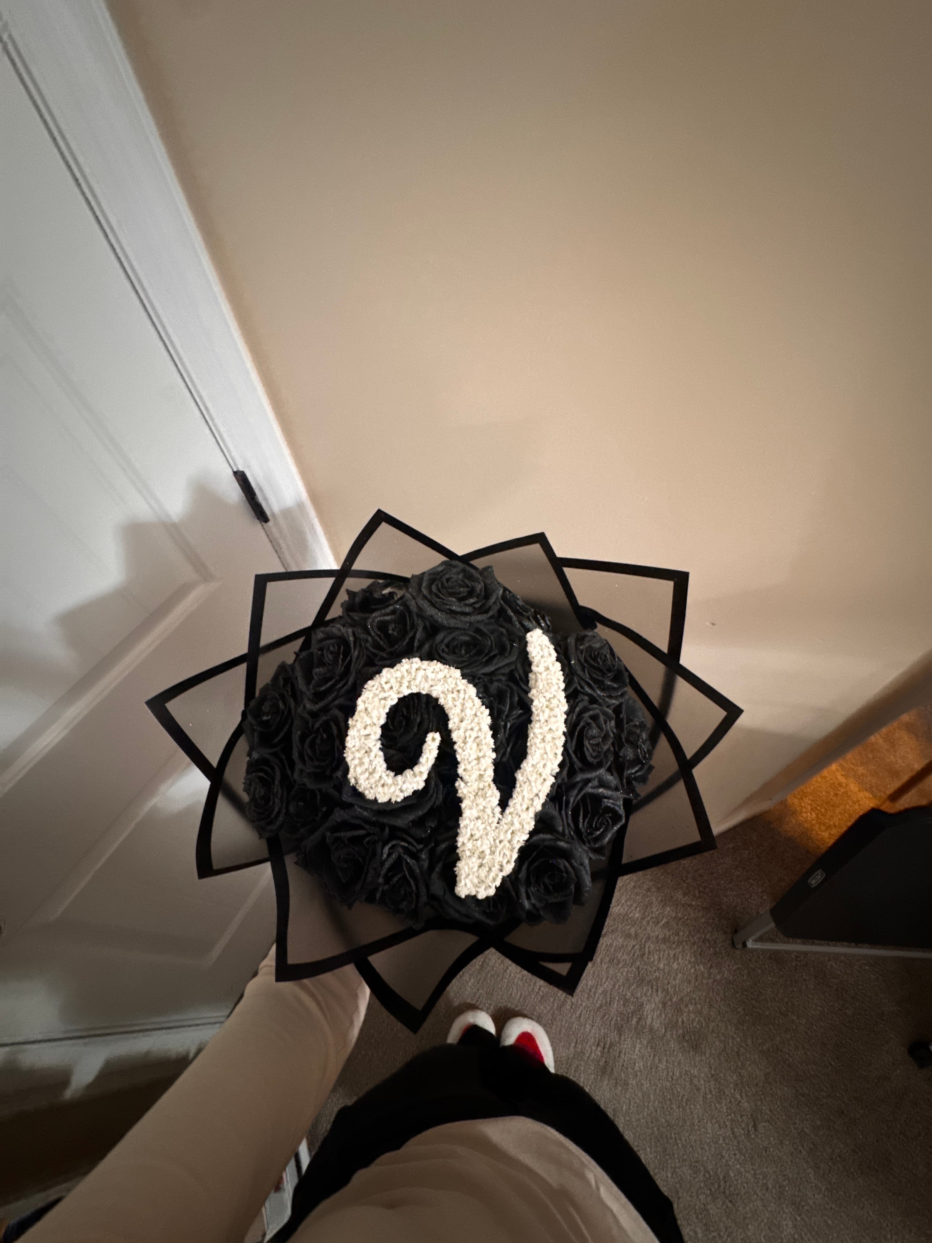 Black roses with a letter S monogram in white baby's breath, in a black star-shaped wrap