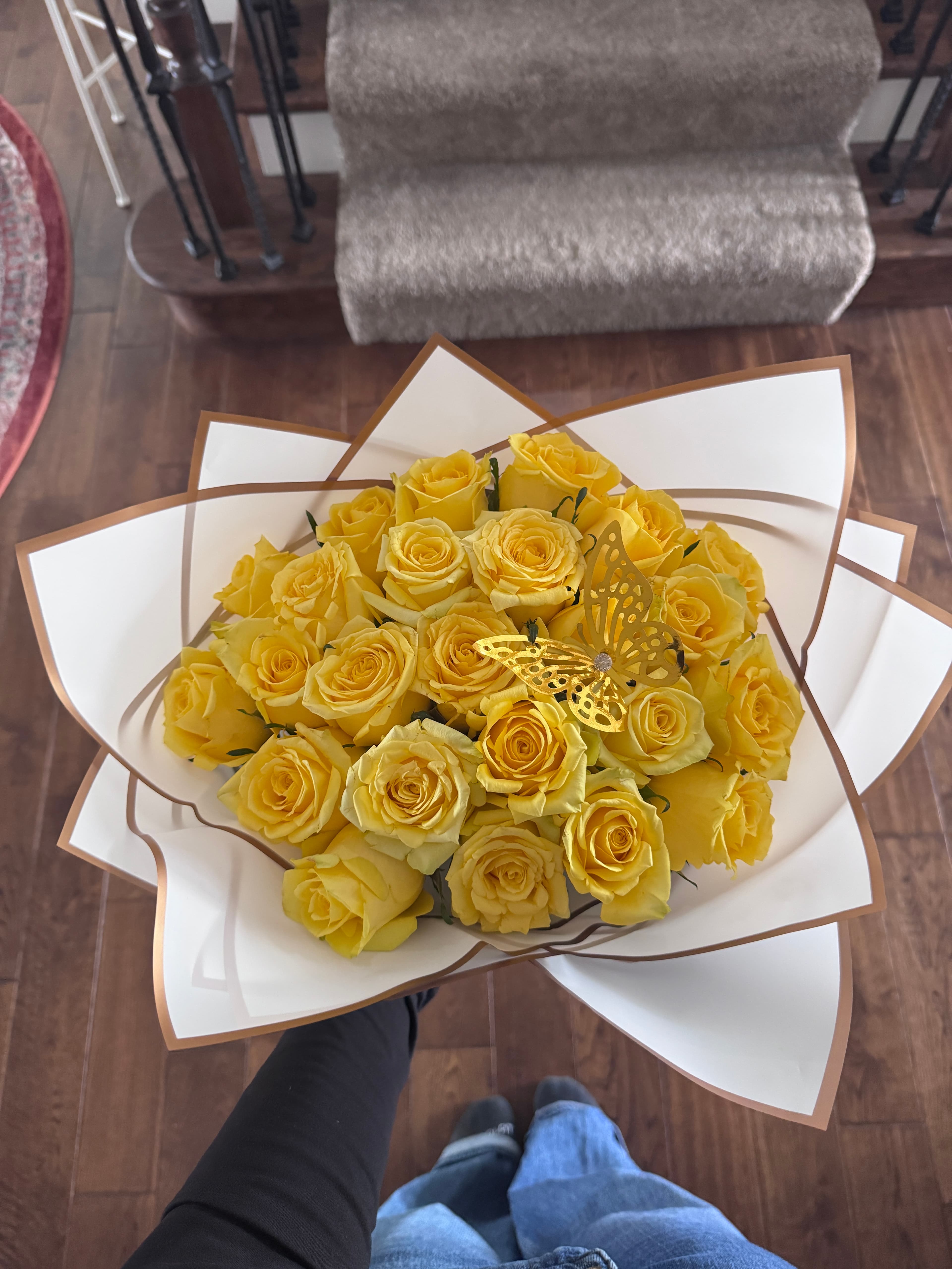 Yellow roses in white and gold wrap topped with a gold butterfly ornament