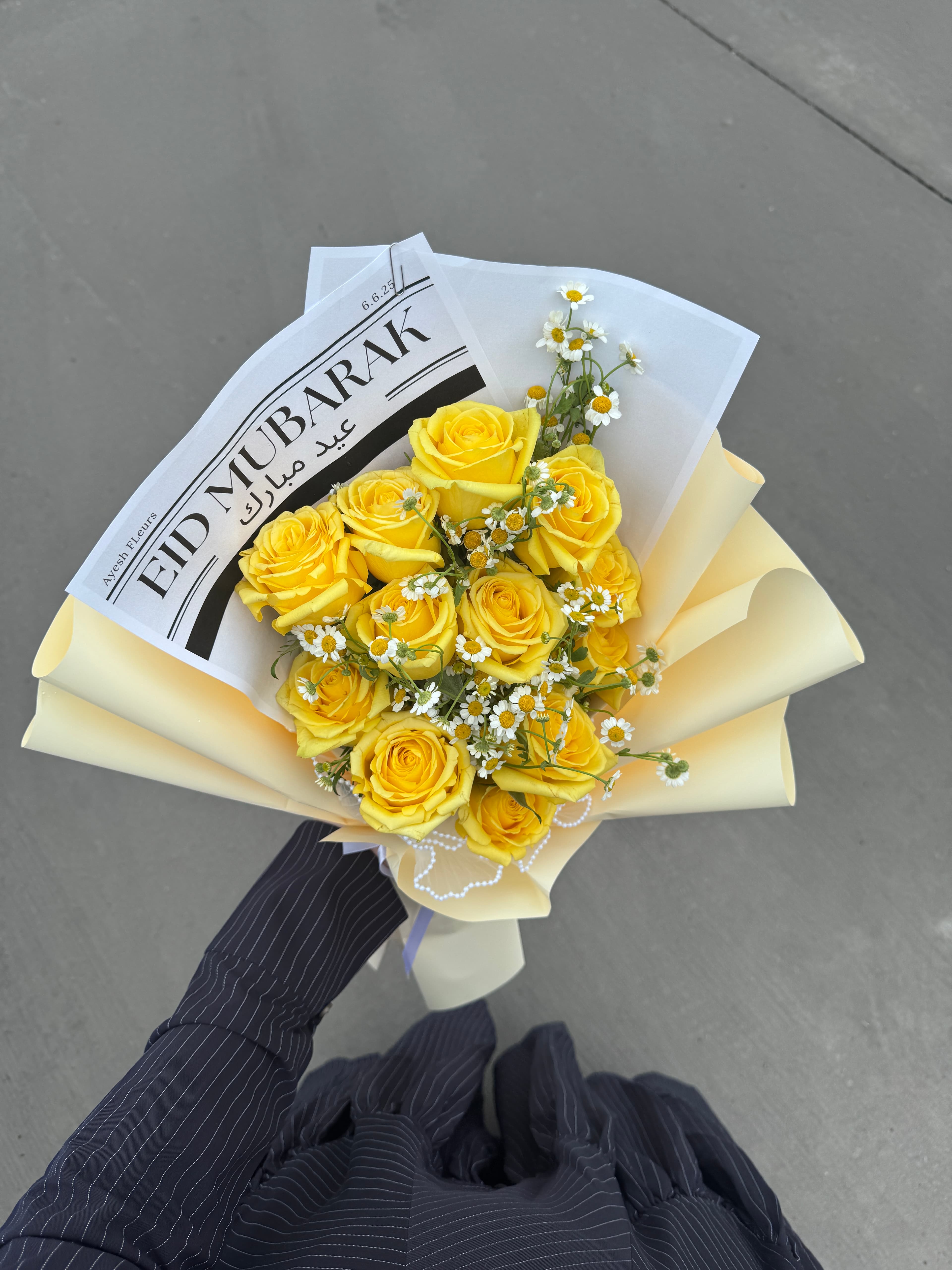 Yellow roses and daisies in cream wrap with Eid Mubarak newsprint paper