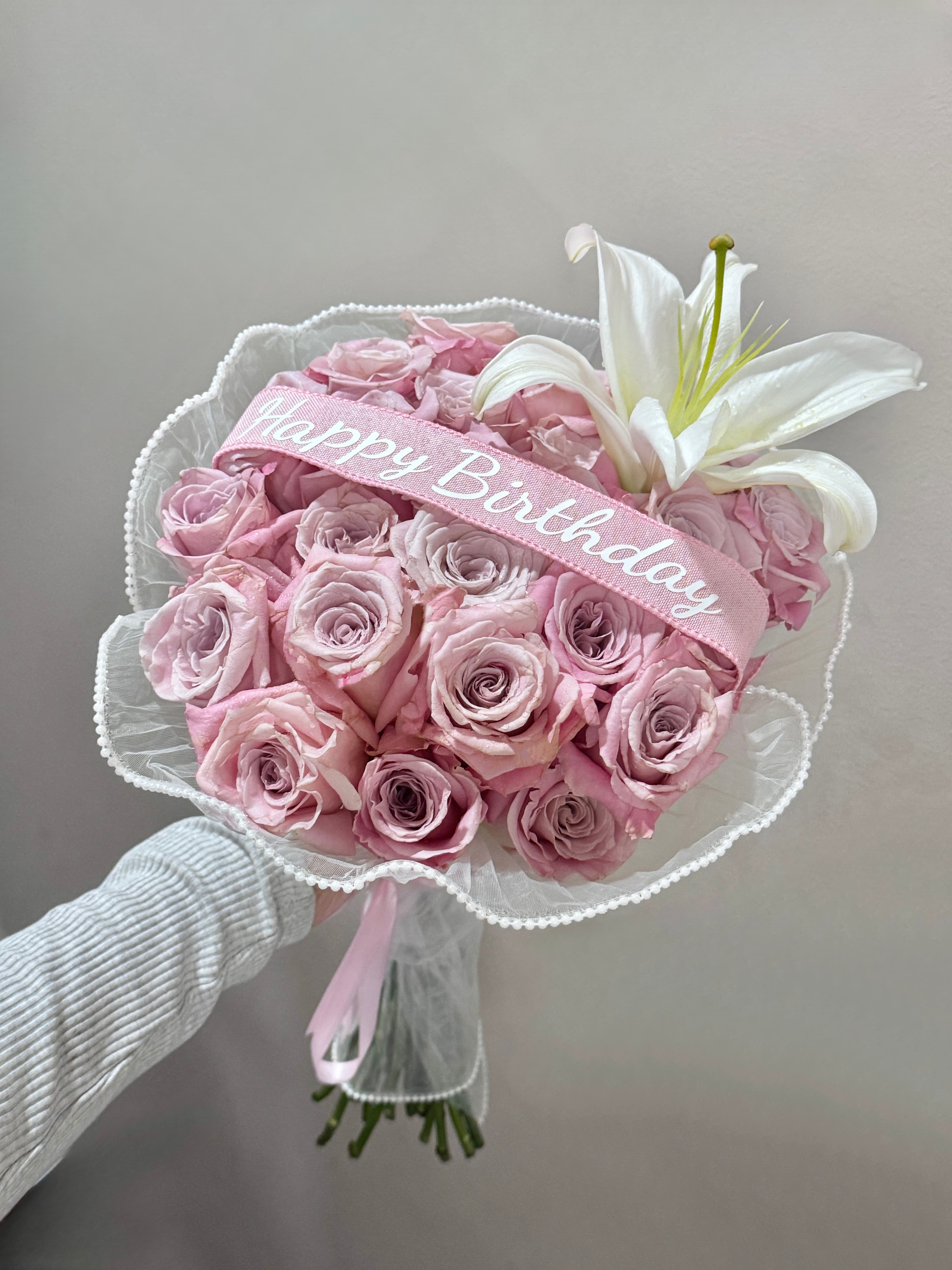 Dusty pink rose bouquet with a white lily and pearl trim, sash ribbon reading Happy Birthday